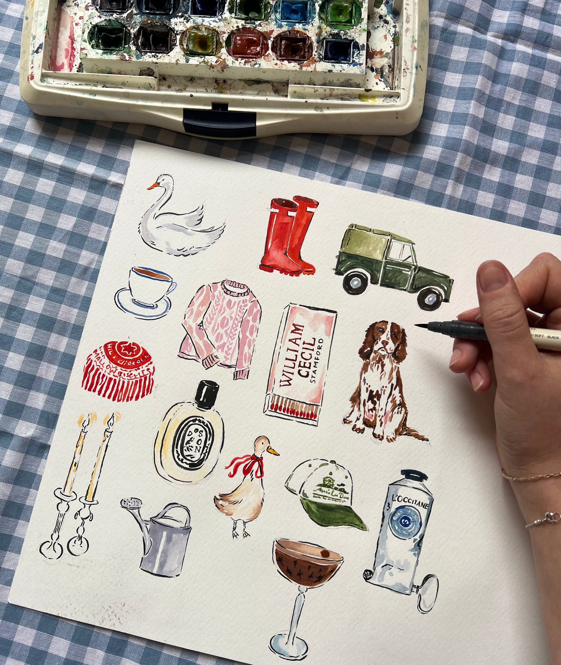 Artistic illustration of various objects on a checkered fabric background with watercolor set.